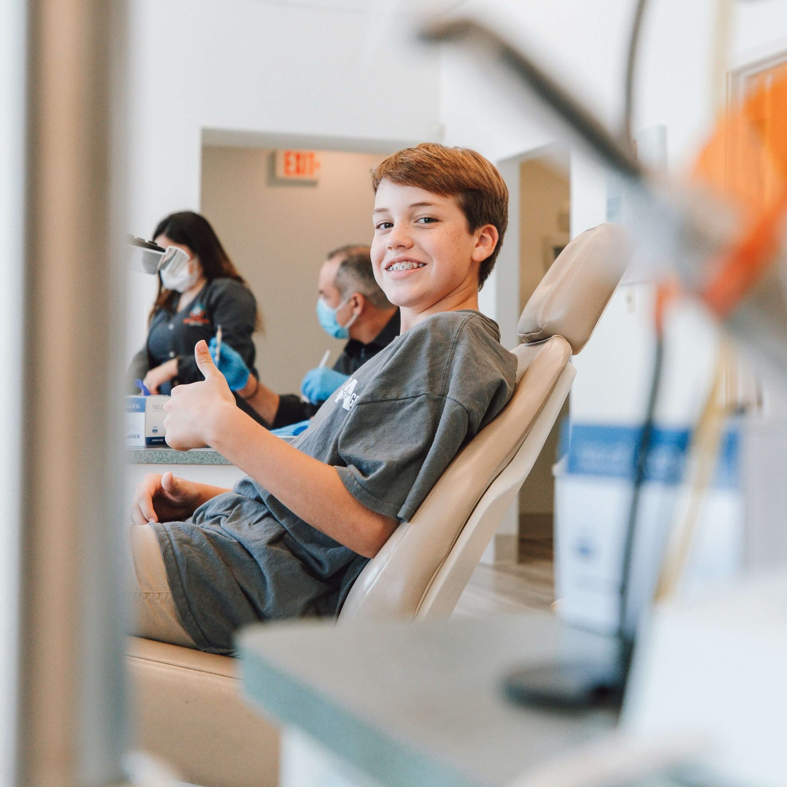 smiling boy in dental chair making thumbs-up sign